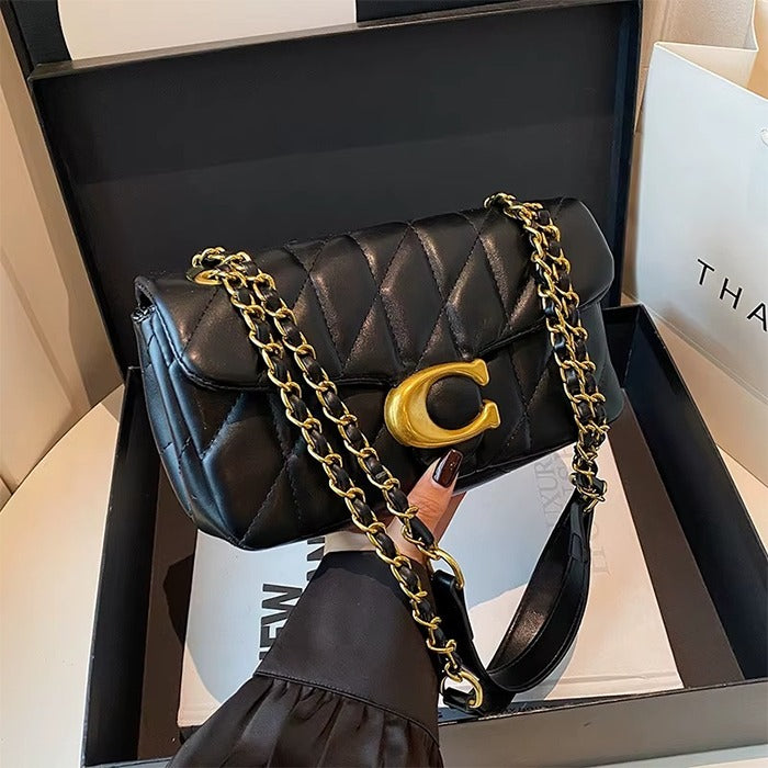 Black quilted handbag with gold chain and clasp in a box