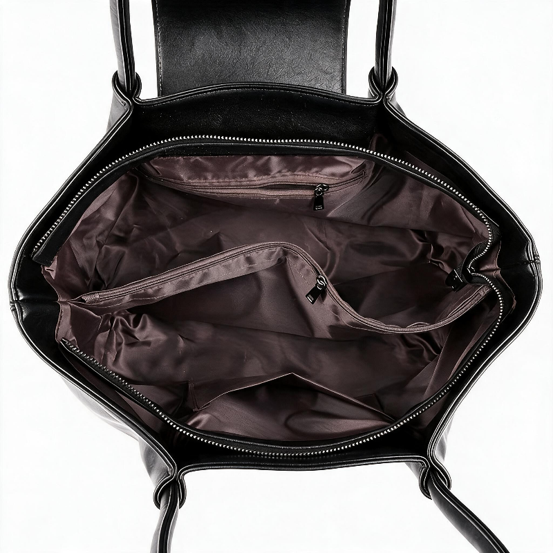 Open black handbag showing the interior with a dark brown satin lining, zippered main compartment, and interior pockets on a white background.