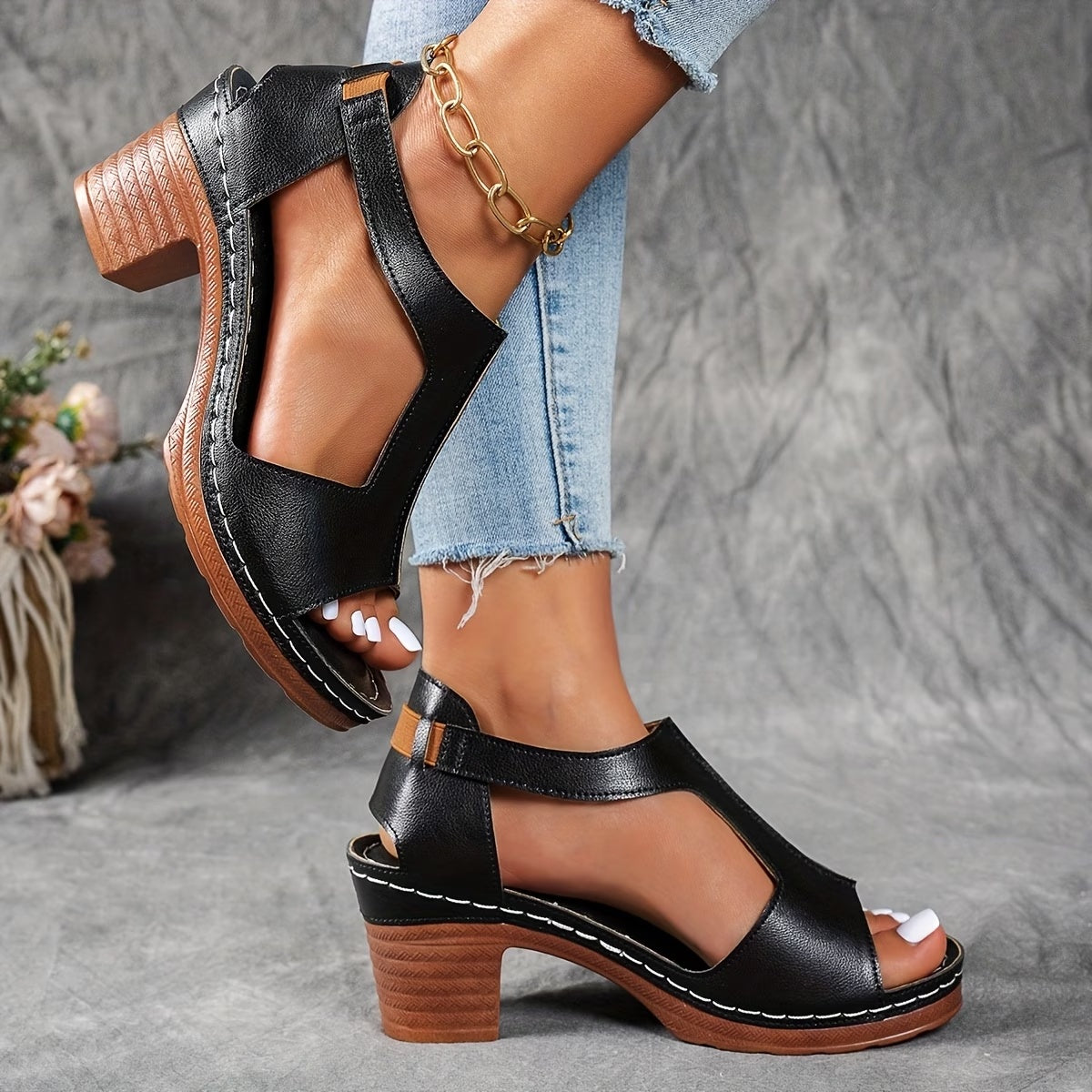 Black sandals with wooden soles worn by a person on a gray background