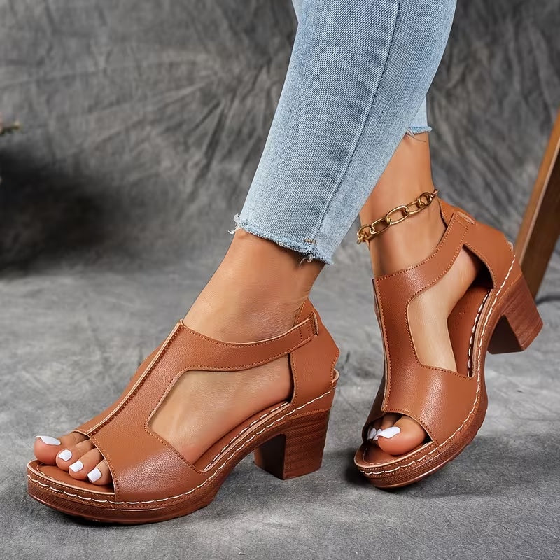 Brown open-toe sandals worn with light blue jeans on a gray background