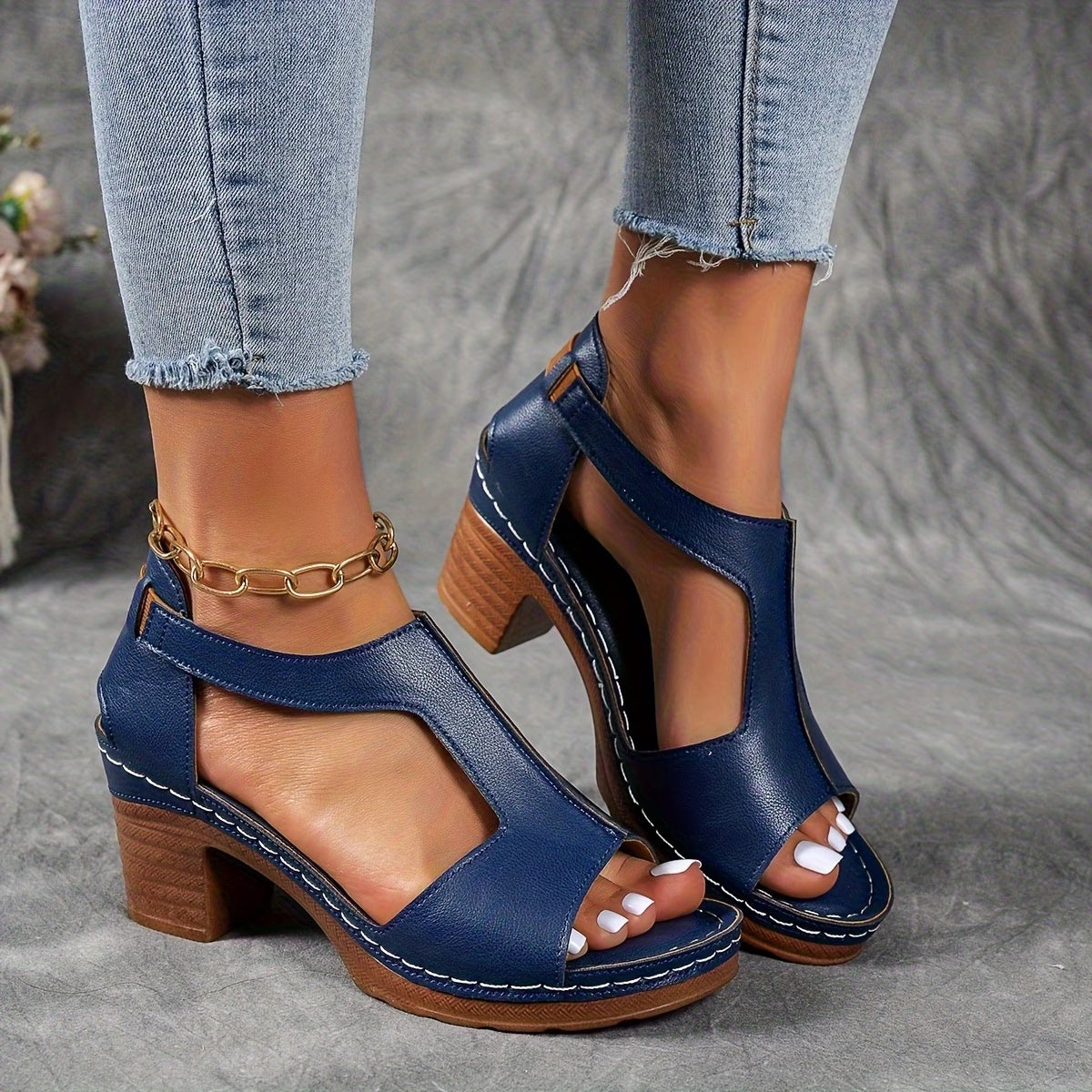 Blue sandals with wooden block heels worn with light blue jeans on a gray background