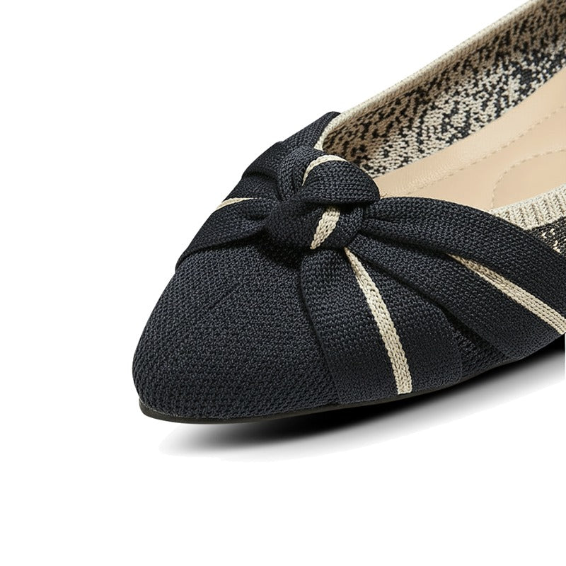 Black flat shoe with a bow detail on a white background